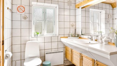 Yere oturan klozetli, beyaz fayanslı ve ahşap banyo mobilyalı bir banyo (© @triner2 and @strandparken3)