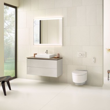 Geberit'ten aynalı dolap, lavabo dolabı, kumanda kapakları ve vitrifiyeler içeren bej banyo