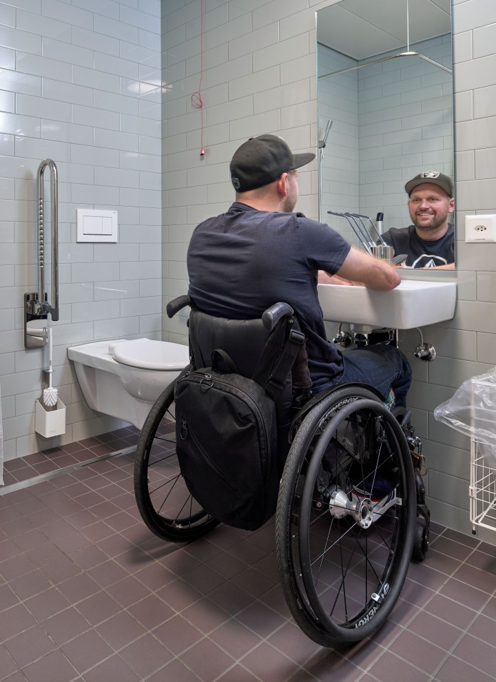 Tekerlekli sandalyedeki Peter Roos engelsiz banyodaki lavabo alanında (© Ben Huggler)
