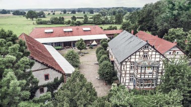 Kuzey Almanya'da Waddeweitz'te geniş bir arazinin üzerinde aralarında ahşap karkaslı bir evin de bulunduğu çeşitli binalar (© Geberit)
