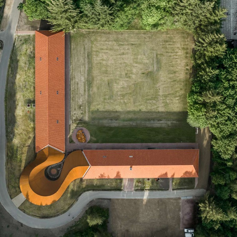 Yukarıdan görünümde iki tarihi binayı kiremit çatılarla birbirine bağlayan yeni yuvarlak bina gösterilmektedir (© R_Hjortshoj) Yukarıdan görünümde iki tarihi binayı kiremit çatılarla birbirine bağlayan yeni yuvarlak bina gösterilmektedir (© R_Hjortshoj)