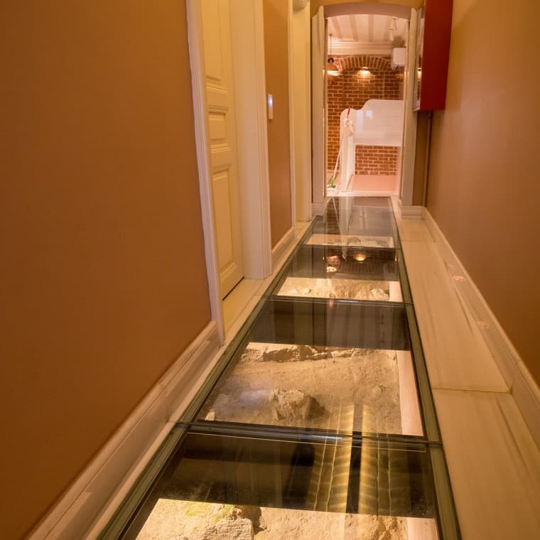 Zemin kattaki koridorlarda, eski saray bahçesi duvarının antik kalıntıları cam zemin döşeme panellerinin arkasından izlenebilir. (© Haydar Erçin) Zemin kattaki koridorlarda, eski saray bahçesi duvarının antik kalıntıları cam zemin döşeme panellerinin arkasından izlenebilir. (© Haydar Erçin)